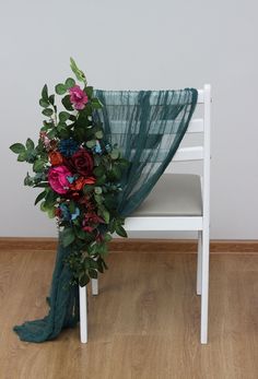 a bouquet of flowers sitting on top of a white chair next to a green scarf