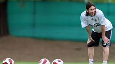 a man standing next to two soccer balls