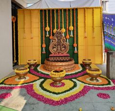 a decorated stage with yellow curtains and flowers on the floor, in front of a green door