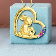 The Personalized Fox Family Birthstones Necklace in Stainless Steel offers a unique and charming way to honor the close-knit bond of a family. This delightful piece features an adorable fox family, with the adult fox embracing its cub, both rendered in a warm gold-tone. The pendant is accented with up to three birthstones, each representing a family member, and can be customized with names engraved along the circular frame, symbolizing the protective and nurturing circle of family life. This whi Personalized Jewelry For Easter Gifts, Family Birthstone Necklace, Personalized Bunny, Birthstone Necklace, Gold Tones, Knitting, Pendant, Gold