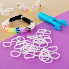 several bracelets and rubber bands laid out on top of a purple paper with scissors