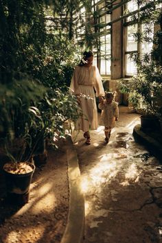 a woman and child walking through a greenhouse