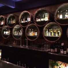 several wine barrels are stacked on the wall behind a bar with liquor bottles in it