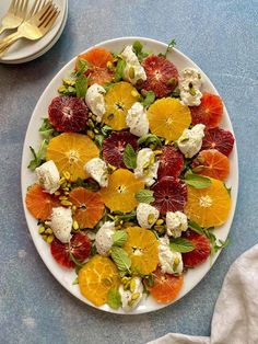 a white plate topped with oranges, raspberries and goat cheese on top of a blue table