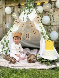 a baby is sitting in front of a teepee