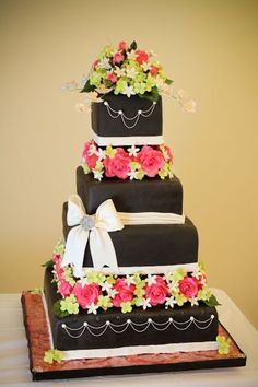 a three tiered cake decorated with flowers and ribbons