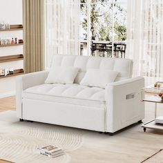 a white couch sitting on top of a wooden floor next to a book shelf filled with books