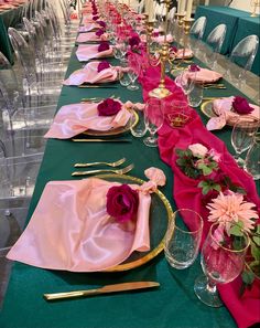 the table is set with pink napkins and gold place settings