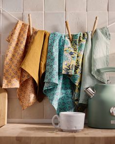 a tea kettle sitting on top of a wooden counter next to a cup and napkins