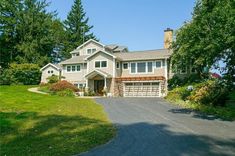 a large house with lots of trees in the front yard and driveway leading up to it