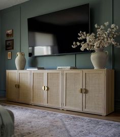 an entertainment center with vases and flowers in front of a flat - screen tv