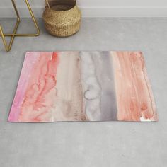 an abstract rug with pink, grey and orange colors on the floor next to a basket