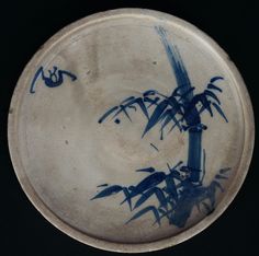 a blue and white plate with bamboo trees painted on the side, in front of a black background