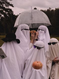 several people dressed in white are holding an umbrella over their heads and one person is covering her face