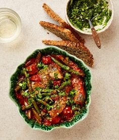 a green bowl filled with vegetables next to bread sticks