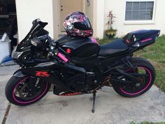 a motorcycle parked in front of a house with pink accents on it's fenders