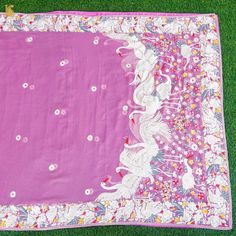 a pink and white blanket laying on top of green grass