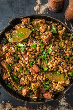 a skillet filled with beans and greens on top of a table