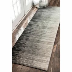 a gray and black area rug in front of a white door with wooden flooring