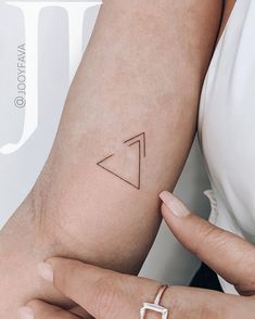 a woman's arm with a small triangle tattoo on the left side of her arm