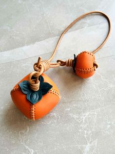 an orange leather bag with a flower on the front and two strings attached to it