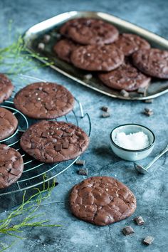 chocolate cookies cooling on a wire rack next to a bowl of sea salt and spoons