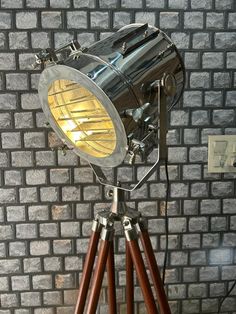 an old fashioned camera on a tripod in front of a brick wall with a spotlight