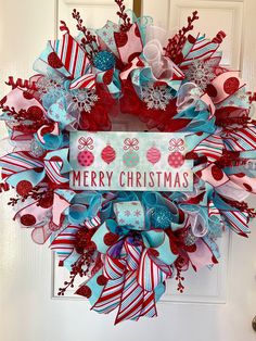 a merry christmas wreath on the front door with red, white and blue ribbon around it