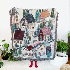 a woman is standing in front of a quilt with houses on it and red boots