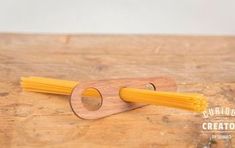 a wooden object with some yellow pasta on it's end and a hole in the middle