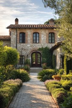 a stone house surrounded by greenery and trees in front of the entrance to it