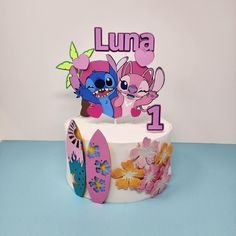 a birthday cake decorated with cartoon characters and flowers on a blue table topper that says lunaa 1