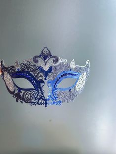 Designed to mesmerize, this extraordinary Blue mask is adorned with stunning blue sapphire rhinestones, making it an absolute show-stopper! Embellished with glitter for an added touch of glamour, making you and your partner stand out among the crowd. Be the center of attention at masquerade balls, proms, Halloween parties, or any event that demands a touch of elegance and mystery. Age Group/Gender - Adult/Unisex Size/Type - One size fits all adults Mask Color - Navy Glitter Color - Silver and na Elegant Blue Masquerade Mask For Parties, Elegant Blue Eye Mask For Masquerade, Elegant Silver Evening Masks, Blue Venetian Masquerade Mask For Party, Blue Eye Mask For Carnival, Elegant Blue Mask For Masquerade, Blue Venetian Masks For Masquerade, Blue Masquerade Mask For Mardi Gras, Blue Venetian Eye Mask