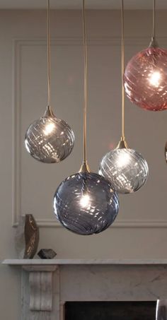 four glass balls hanging from a ceiling in front of a fire place with a fireplace