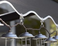 several metal lamps hanging from a line outside