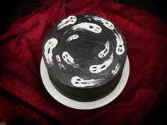 a black and white decorated cake on a red tablecloth with skulls around the edges