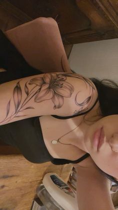 a woman with a flower tattoo on her arm and shoulder is sitting in front of a mirror