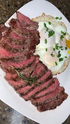 steak, eggs and grits on a white plate sitting on a granite counter top