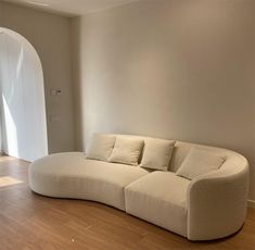 a white couch sitting in the middle of a living room next to a doorway with an arched window