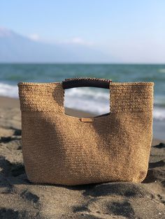 a straw bag sitting on top of a sandy beach next to the ocean with waves coming in