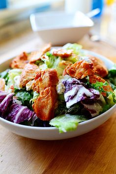 a white bowl filled with salad on top of a wooden table