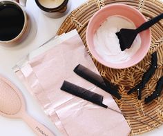 some hair brushes are sitting on a table next to two cups and a paper bag