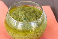 a glass jar filled with pesto sauce on top of a pink napkin next to a spoon