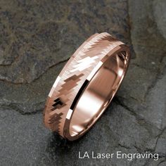 a rose gold wedding ring with an intricate design on the outside and inside, sitting on top of a rock