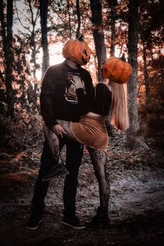 a man and woman dressed up as jack - o'- lanterns in the woods