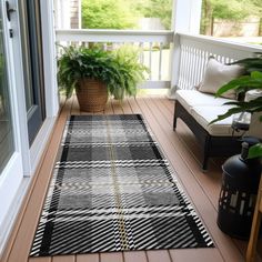 a black and white rug sitting on top of a wooden floor next to a potted plant