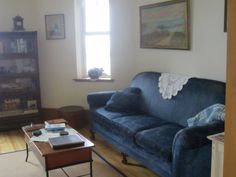 a living room with a blue couch and coffee table in front of a book shelf