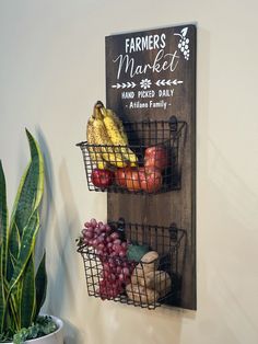 a couple of baskets filled with fruit on top of a wooden wall mounted shelf next to a potted plant