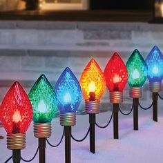 christmas lights are lined up in front of a fireplace with snow on the ground behind them