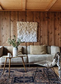 a living room with wood paneling and white couches, rugs on the floor